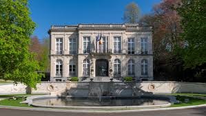 Plombier Auderghem devant l'hôtel de ville moderne entouré de commerces et de verdure en centre-ville dynamique.