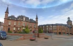 Plombier Frameries : rue animée avec maisons en brique typiques, façades colorées et commerces locaux.