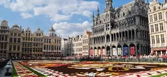 Plombier Mouscron : rue animée avec façades typiques, enseignes locales et présence d'un plombier au travail.