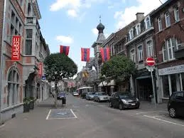 Vue de Visé avec un plombier local devant la collégiale Saint-Hadelin, architecture typique et réparations en cours